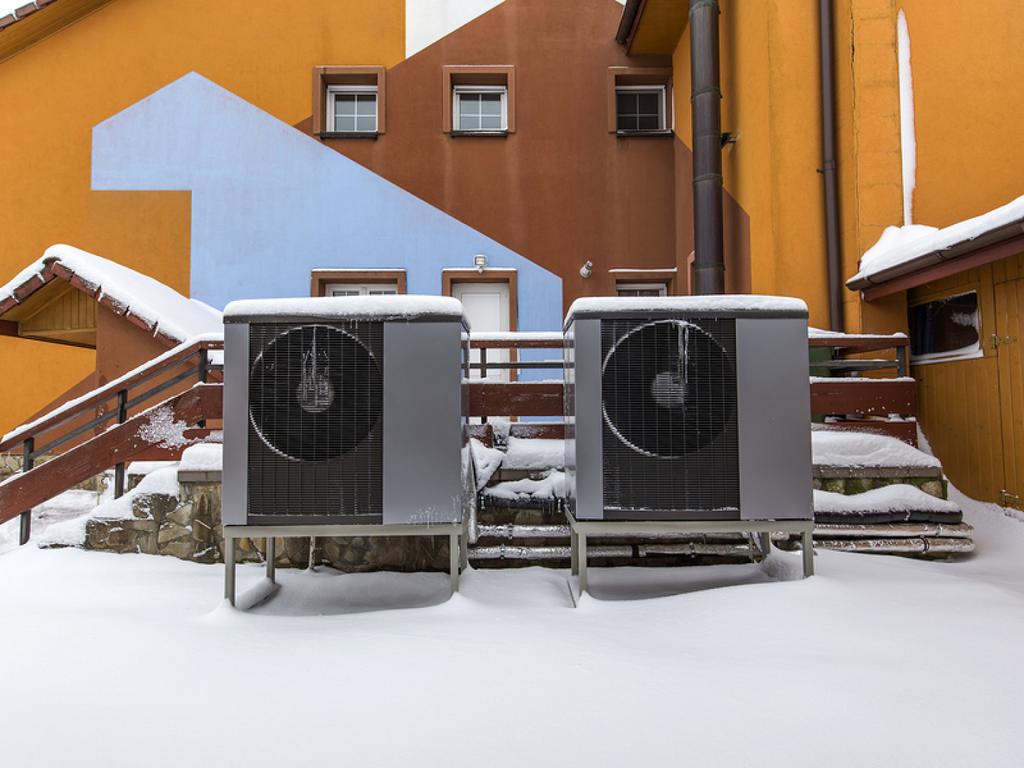 Air conditioning units covered in snow outside.
