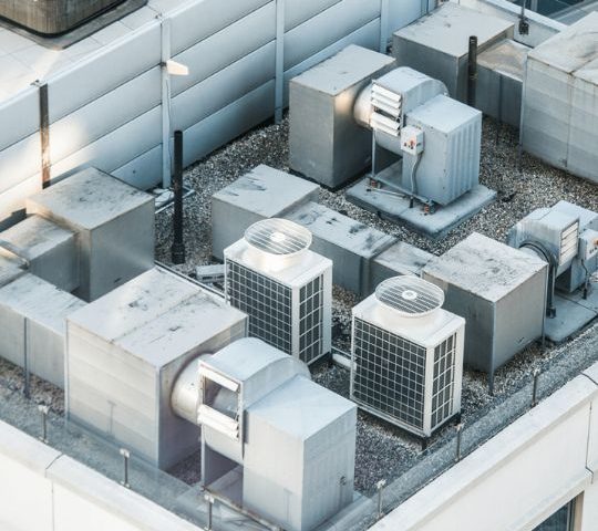 Top view of HVAC units on a rooftop in a city setting.
