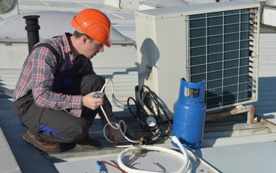 Technician repairing an air conditioning unit on a rooftop.
