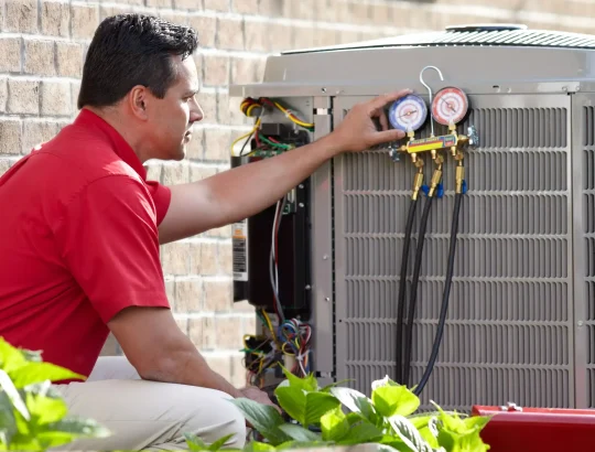 Technician inspects HVAC system with pressure gauges outdoors.